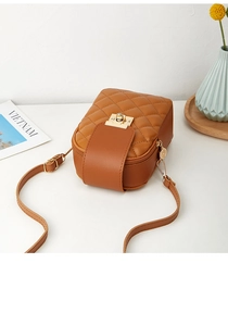 Close-up of quilted pattern and gold metal clasp on a brown leather mini crossbody bag