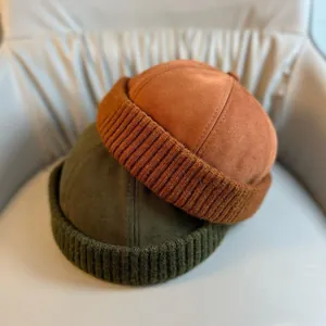 Detail of corduroy docker hats in brick red and olive green with knitted brims