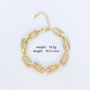 Detalle de pulsera de eslabones dorados con incrustaciones de circón y dije de corazón