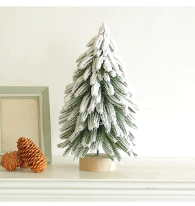 Close-up of a mini white flocked Christmas tree with realistic snow on a wooden base