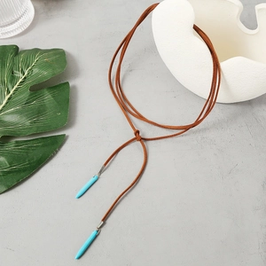 Detail of Bohemian suede cord necklace featuring vibrant turquoise pendant drops