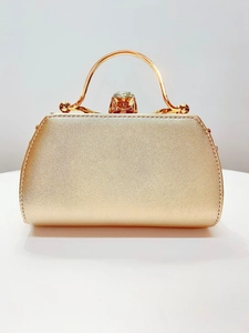 Detail of elegant gold evening bag featuring metallic shine and a crystal-encrusted clasp