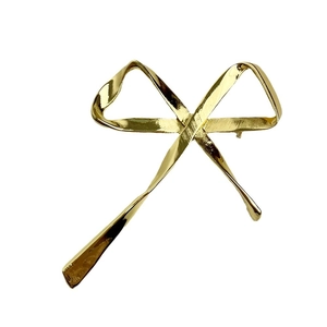 Elegant gold metal ribbon bow brooch with polished finish and fluid design on white background