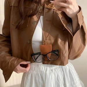 Close-up of caramel brown leather glasses pouch necklace worn by a stylish model