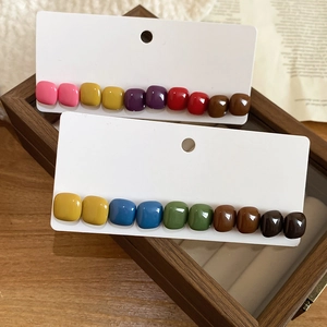 Close-up of colorful resin square stud earrings in a vintage wooden jewelry display box