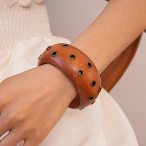 Macro detail of warm orange wooden cuff bracelet featuring vintage metal eyelet rivets