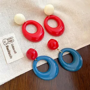 Boucles d'oreilles pendantes ovales en résine rouge, bleue et blanc crème sur lin
