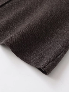 Vue macro du gilet en tricot marron foncé montrant la texture fine et le détail de couture