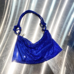 Detailed view of royal blue rhinestone shoulder bag with decorative knotted strap detail
