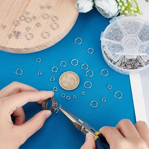 Detail of silver stainless steel jump rings being used with jewelry tools for DIY crafts