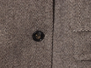 Macro shot of herringbone wool blend fabric with textured black button detail