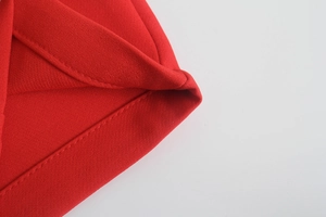 Dettaglio dei pantaloni rossi a vita alta con trama in twill e cuciture di precisione