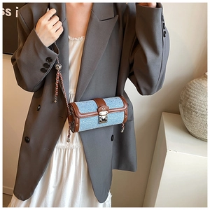 Detail of tweed cylinder bag with metallic M-buckle, silver chain and leather trim
