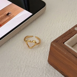 Polished S925 sterling silver heart-shaped open ring in gold on a warm textured surface