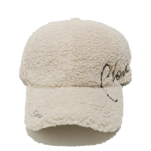 Detail of beige sherpa fleece baseball cap with cursive embroidery and fuzzy texture
