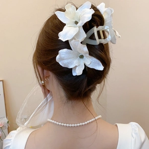 Detailed back view of a white fabric flower hair claw clip worn by a model in a bun