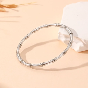 Detailed close-up of a silver stainless steel bamboo style bangle on a white stone base