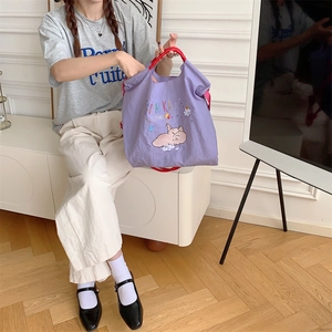 Detail of cute elephant embroidery on purple nylon tote bag with red handles