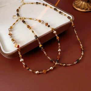 Detailed view of faux tiger eye beaded necklace with gold accents in a white gift box
