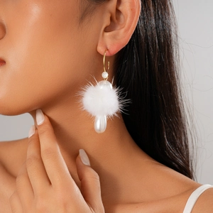 Detail of C-shaped hook earring featuring a plush pompom and drop faux pearl charm
