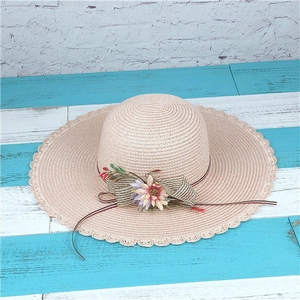 Detail von Strohhut in Beige mit gewelltem Rand und dekorativer Blumenschleife
