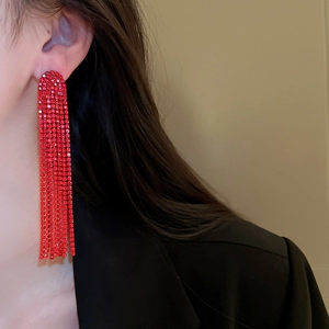 Close-up of red long fringe tassel earring with sparkling rhinestones on model ear