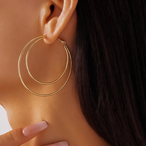Close-up of double layered gold geometric hoop earrings worn by a female model