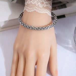 Detailed view of silver braided metal knot bangle with textured industrial design on wrist
