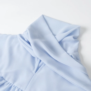 Vista dettagliata del collo della camicia in chiffon azzurro con eleganti pieghe e design incrociato