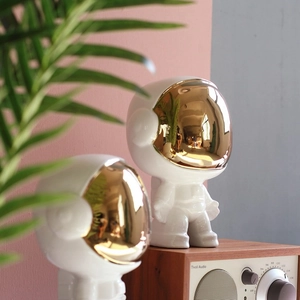 Moderne Astronauten-Figur aus weißer Keramik mit Goldvisier auf einem Schreibtisch