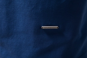 Close-up of navy blue jersey fabric with a metallic brand tag and textured knit pattern