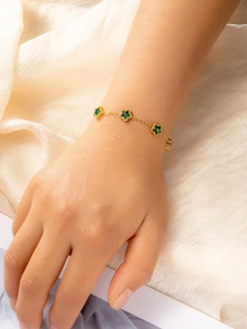 Close-up of a gold titanium bracelet with three green star-shaped zircons on silk