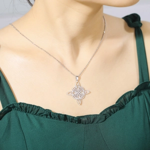 Detail view of silver Celtic Witch's Knot necklace worn on a green fabric background