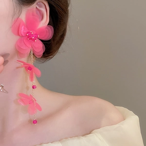 Detail of pink chiffon flower tassel earrings worn by a model in a close-up profile view