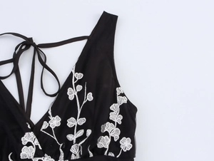 Détail du décolleté en V profond avec broderies florales blanches sur robe noire
