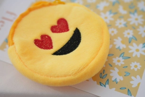 Macro shot of yellow plush round coin purse with heart eyes embroidered smiley face
