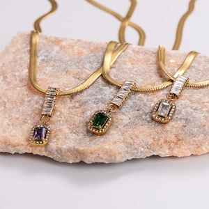 Dettaglio macro di pendenti geometrici con zirconi viola, verdi e bianchi su catene d'oro