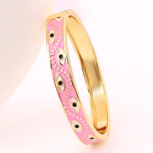 Detail of pink enamel evil eye charm on polished gold-plated bangle for women