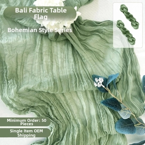 Detail of sage green cheesecloth table runner with bohemian textured gauze and raw edges