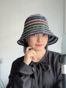 Detailed close-up of handmade crochet bucket hat with colorful stripes on a female model