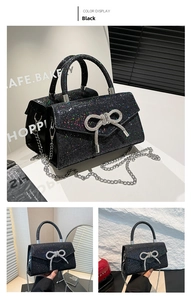 Detail of black glitter evening bag with rhinestone bow and silver metal handle