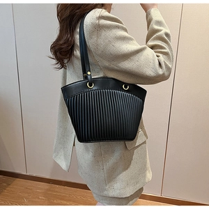 Detail of black tote bag with vertical pleated texture and golden hardware rings