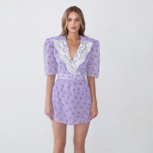 Détail de mini-robe fleurie violette avec col en V en dentelle blanche et ceinture