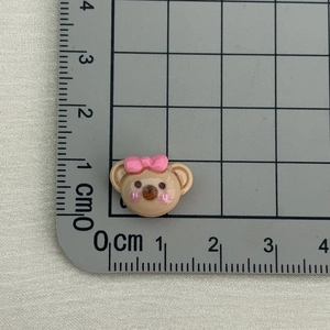 Miniature brown resin bear charm with pink bow and ruler showing 1.5cm size detail