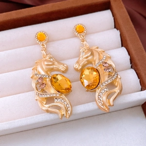 Détail des boucles d'oreilles tête de cheval dorées avec strass champagne incrustés