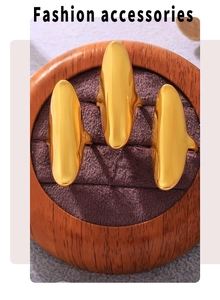Three polished gold irregular rings displayed on a premium purple velvet wooden jewelry stand