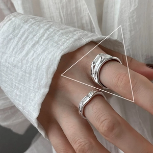 Detailed view of silver liquid metal rings featuring irregular textures on a hand