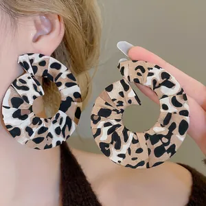 Chic leopard print fabric hoop earrings with twisted design worn by model