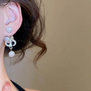 Detailed view of silver hoop earrings with diamond encrusted CD motif and dual pearls