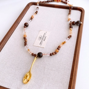Détail d'un collier vintage avec perles en bois et pendentif cuillère dorée unique